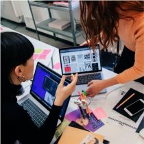 Image of two people working at a desk on their laptops